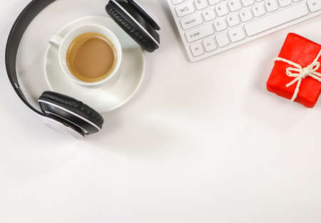 Top view or Flat lay of coffee cup , headphones, white computer keyboard and red gift box on white background with copy space. Seasonal holidays and  coffee time concept.の写真素材