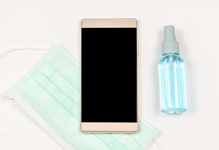 Close up image of blank screen of mobile phone on white background with medical face mask and...