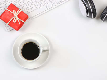 Top view or flat lay of coffee cup, computer keyboard, red gift box and headphones on white  background. Positive morning routine and seasonal holiday concept.の写真素材