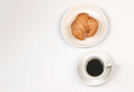 Top view or flat lay of coffee cup and croissant on white  background with copy space. Morning coffee and snack.の写真素材
