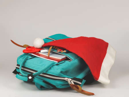 Front view  of  backpack with school supplies and  Christmas Santa hat on white  background with copy space. Christmas party at school concept.の写真素材