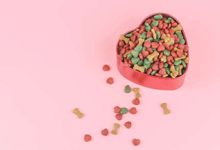 Top view of dried dog food in red heart shape bowl and on pink background. Valentine's day and pet lover concept.の写真素材