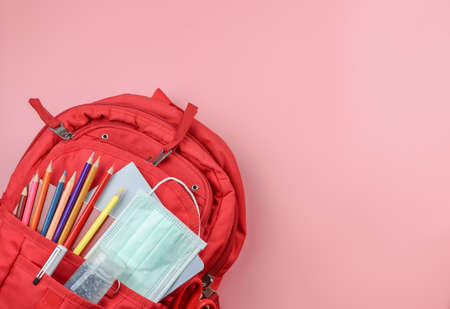 COVID-19 prevention while going back  to school  and new normal  concept. Top view of backpack with school supplies , surgical mask and alcohol sanitizer gel on pink background with copy space.の写真素材