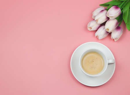 Top view or flat lay of coffee cup  on pink background with tulip flower bouquet. Copy space.の写真素材