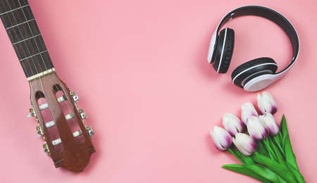 Top view or flat lay of acoustic guitar, tulips bouquet.  white headphones on pink background with copy space. spring, love song and leisure.の写真素材