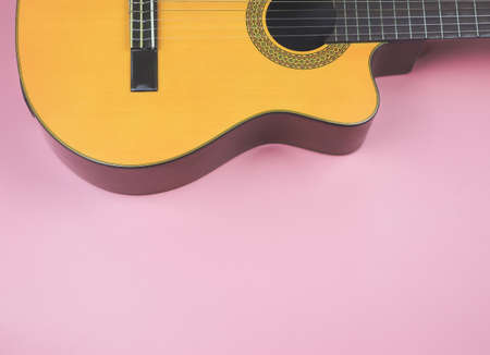 Top view or flat lay of acoustic guitar on pink background with copy space.