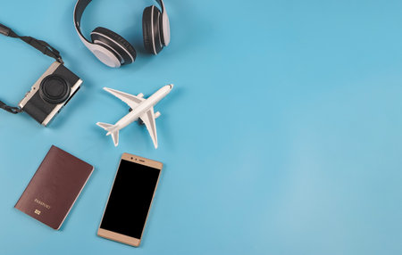 Top view or flat lay of airplane model, passport, camera, headphones and mobile phone on blue...