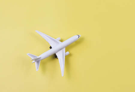 Top view or flatlay of airplane model on yellow background. Traveling or transportation concept.