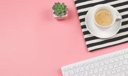 Top view or flat lay of coffee cup on black and white stripes cloth with computer keyboard and cactus in plant pot  on pink background with copy space.の写真素材