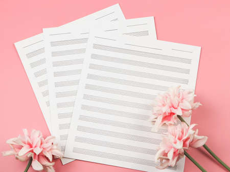 Top view or flat lay of three blank music sheets on pink background with pink flowers decoration.の写真素材