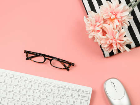 Top view or flat lay of computer keyboard, mouse, eyeglasses, pink flower bouquet on black and white stripes cloth. Business and technology concept.の写真素材