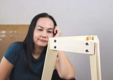 Asian woman  try to assemble knock down furniture and getting confused. Selective focus on furniture.の写真素材