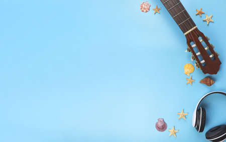 Top view or background  of headphones and acoustic guitar with sea shells and starfishes on blue background, copy space. Summer beach acoustic music background.の写真素材