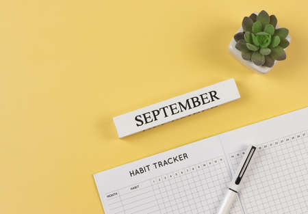 Top view or flat lay of habit tracker book with pen,  succulent plant pot and wooden calendar september on yellow background.の写真素材