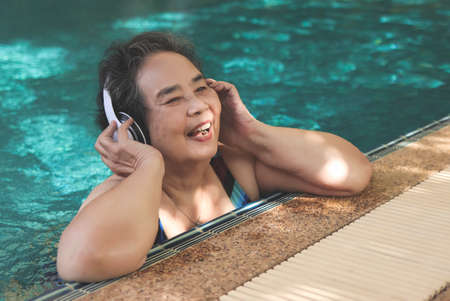 Portrait of  happy and healthy  Asian senior  woman listening to the music with headphones in a...