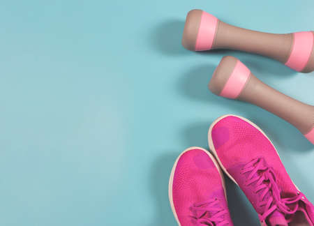 Top view or flat lay of pink sneakers or sports shoes and gray pink dumbbells on pink background with copy space. Sports and active lifestyle concept.の写真素材