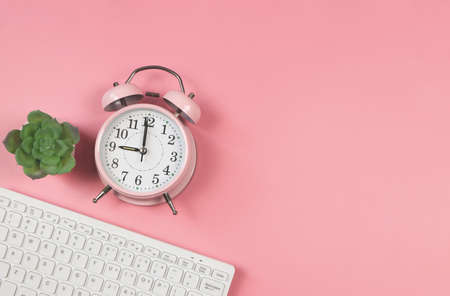 Top view or flat lay of pink vintage alarm clock, computer keyboard and succulent plant pot on pink background with copy space.の写真素材