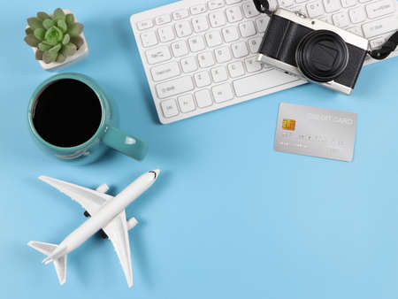 Top view or flat lay of computer keyboard, blue cup of black coffee, airplane model, credit card and succulent plant pot  on blue  background with copy space. Business and Traveling concept.の写真素材
