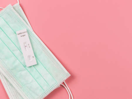 Top view or flat lay of  negative test result antigen test kit (ATK) on medical face masks  on pink...