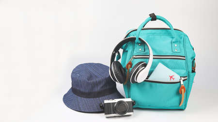 Front view of green backpack with passport cover, headphones, camera and bucket hat  on white background with copy space.. Travel accessories concept.の写真素材
