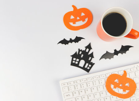 Top view or flat lay of  computer keyboard, coffee cup, halloween decorations, bats and  pumpkin on white background with copy space.の写真素材