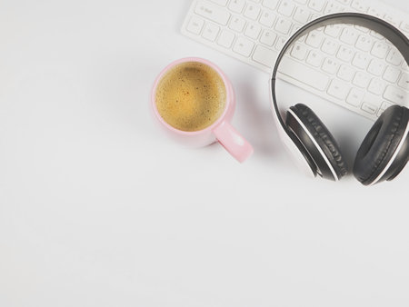 Top view or flat lay of headphones on computer keyboard and pink cup of coffee on white background.の写真素材