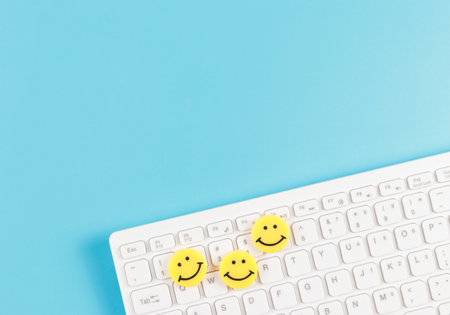 Top view or flat lay of threes smiley faces  on white computer keyboard on blue background.の写真素材