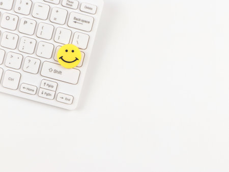 Top view or flat lay of  yellow circle smiling face on white computer keyboard on white  background.の写真素材