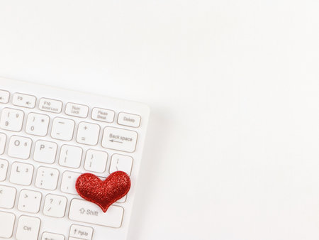 Top view or flat lay of red glitter hearts  on white computer keyboard on white  background. online dating or valentines day concept.の写真素材