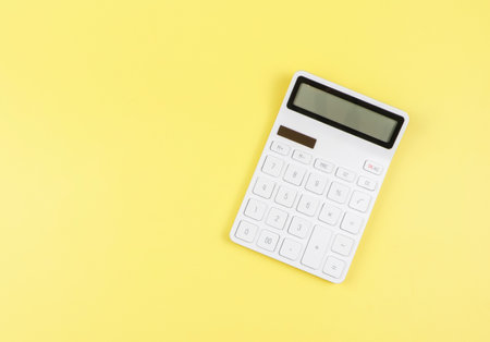 Top view or flat lay of white  calculator on yellow  background with copy space.の写真素材