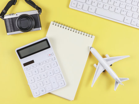 Top view or flat lay of airplane model, computer keyboard, notebook, calculator and digital camera with copy space on yellow background, business and traveling concept.の写真素材