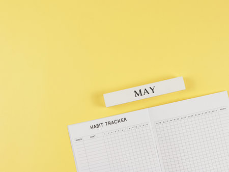 Top view or flat layout of Habit tracker book, wooden calendar May on yellow background with copy space.の写真素材