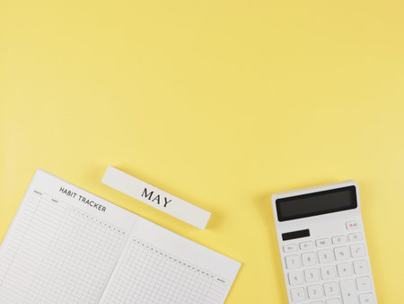 Top view or flat layout of Habit tracker book,  white calculator, wooden calendar May on yellow background.の写真素材