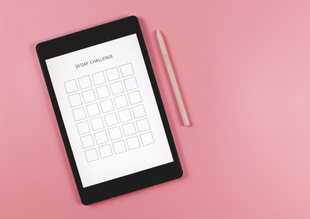Top view or flat lay of digital tablet with template 30 day challenge on screen,  pink stylus pen,  ...
