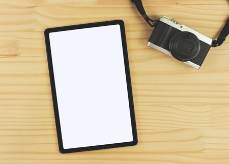 Top view or flat lay of digital tablet with blank white screen and digital camera isolated on wooden table background.の写真素材
