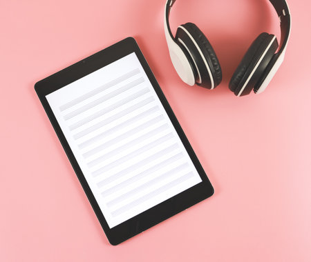 Top view or flat lay of digital tablet with music staff  screen and white headphones on pink background. music composer on digital tablet.の写真素材