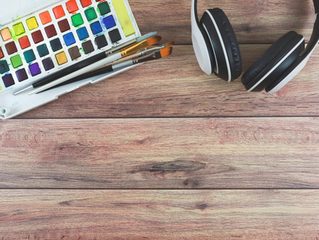 Top view or flat lay of headphones and artist workspace. Drawing tools, stationary supplies on wooden table background with copy space. hobby or leisure concept.の写真素材