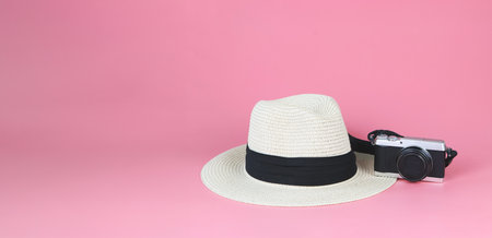 Front view of straw hat and digital camera isolated on pink background. Travelling concept.の写真素材