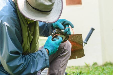 Worker fixing the lawn mower by replace cutting wire.