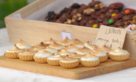 Lemon meringe tarts on wooden board soft focus.の写真素材