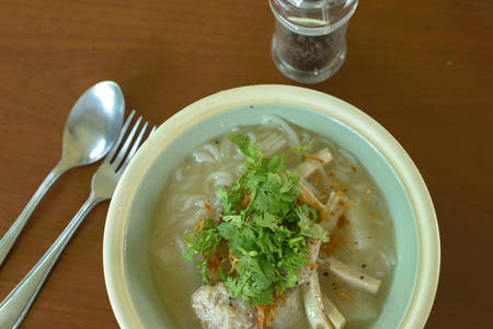 Noodles with minced pork thai style sausage and vegetable on green bowl.