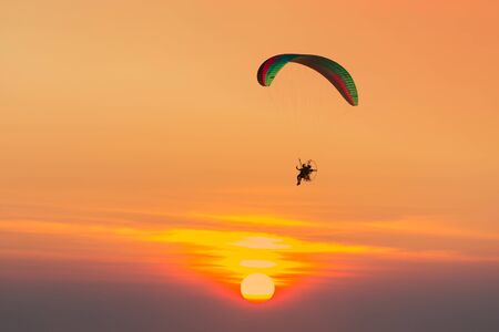 Silhouette of paraglider flying in the evening sky with sunset.の写真素材