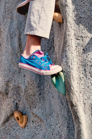 Closeup of pink and blue tennis shoe on foot hold of rock wall.の写真素材