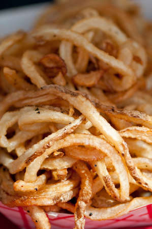 A red and white paper plate overflowing with hot golden french fries.の写真素材
