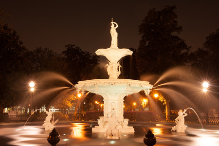 Forsythe Park Fountain with the water fountains working and the spray is reflected in the night light in Savannah, GAの写真素材