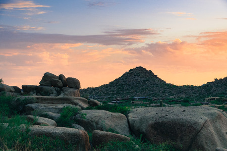 Boulders tower over the desert plants at dawn in the desert park with mountains in background in Scottsdale Arizona.の写真素材