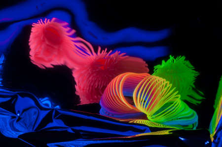 Fuzzy and circular objects which are distorted are viewed in a close-up and are lit with fluorescent colors against a deep blue background.の写真素材