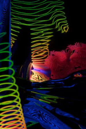 Fuzzy and circular objects in a close-up view and reflections are lit with fluorescent colors against a deep blue background.の写真素材