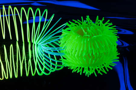 Fuzzy and circular objects which are distorted are viewed in a close-up and are lit with fluorescent colors against a deep blue background.の写真素材