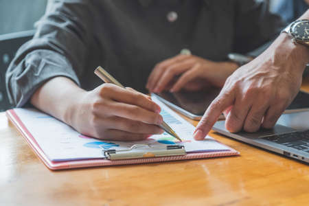 Conceptual image of male and female hands pointing on the same financial chart.の写真素材